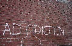 The word addiction written in chalk on a brick wall